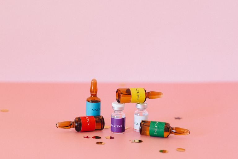 A vibrant arrangement of vaccine ampoules and vials on a pink surface, symbolizing healthcare.