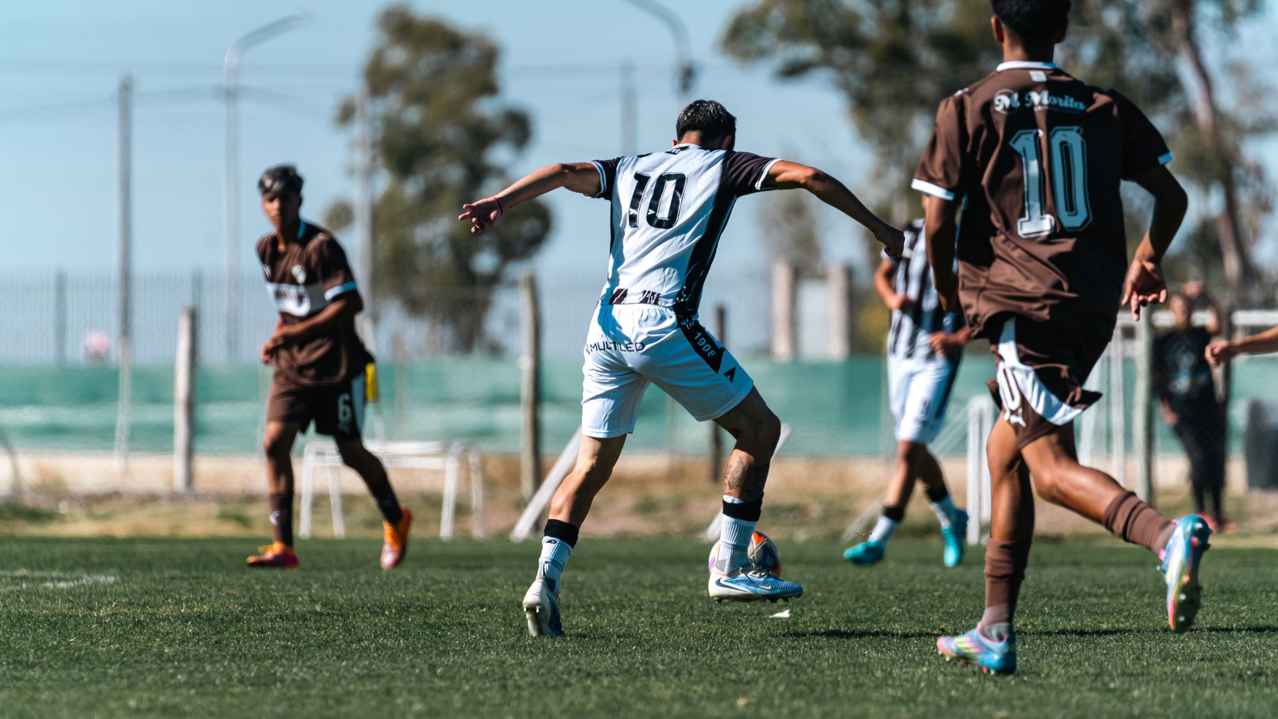 Players compete fiercely in a soccer match on a bright, sunny day, showcasing athleticism and teamwork.