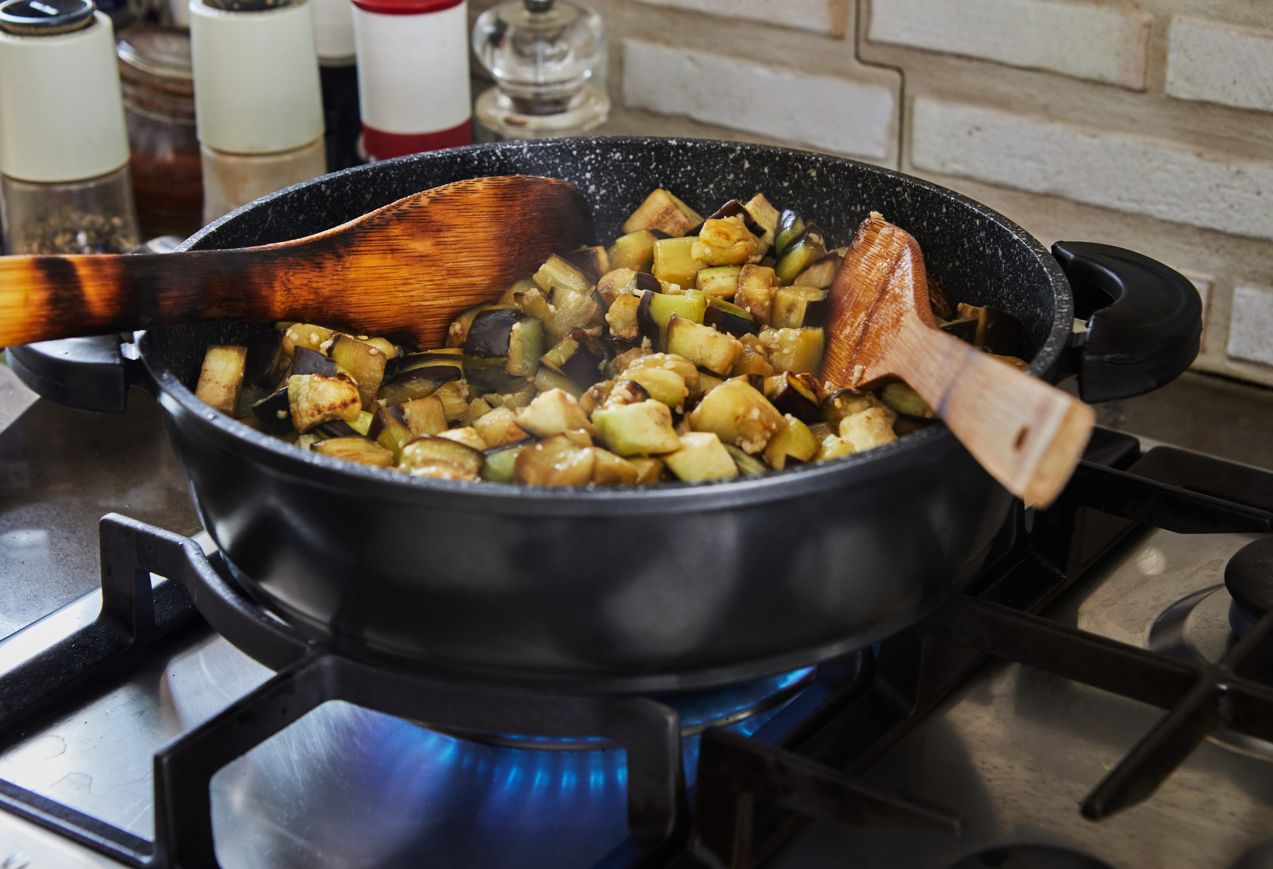 Eggplants are fried in pan on gas stove in the kitchen according to recipe from the Internet.