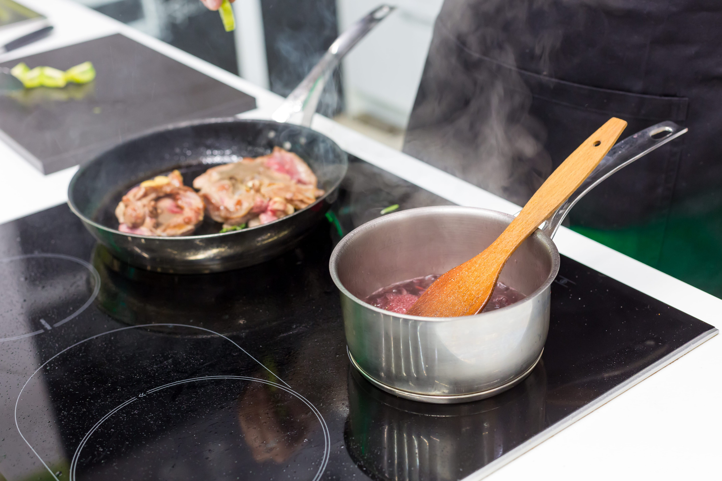 Meat on the frying pan and pot with sauce