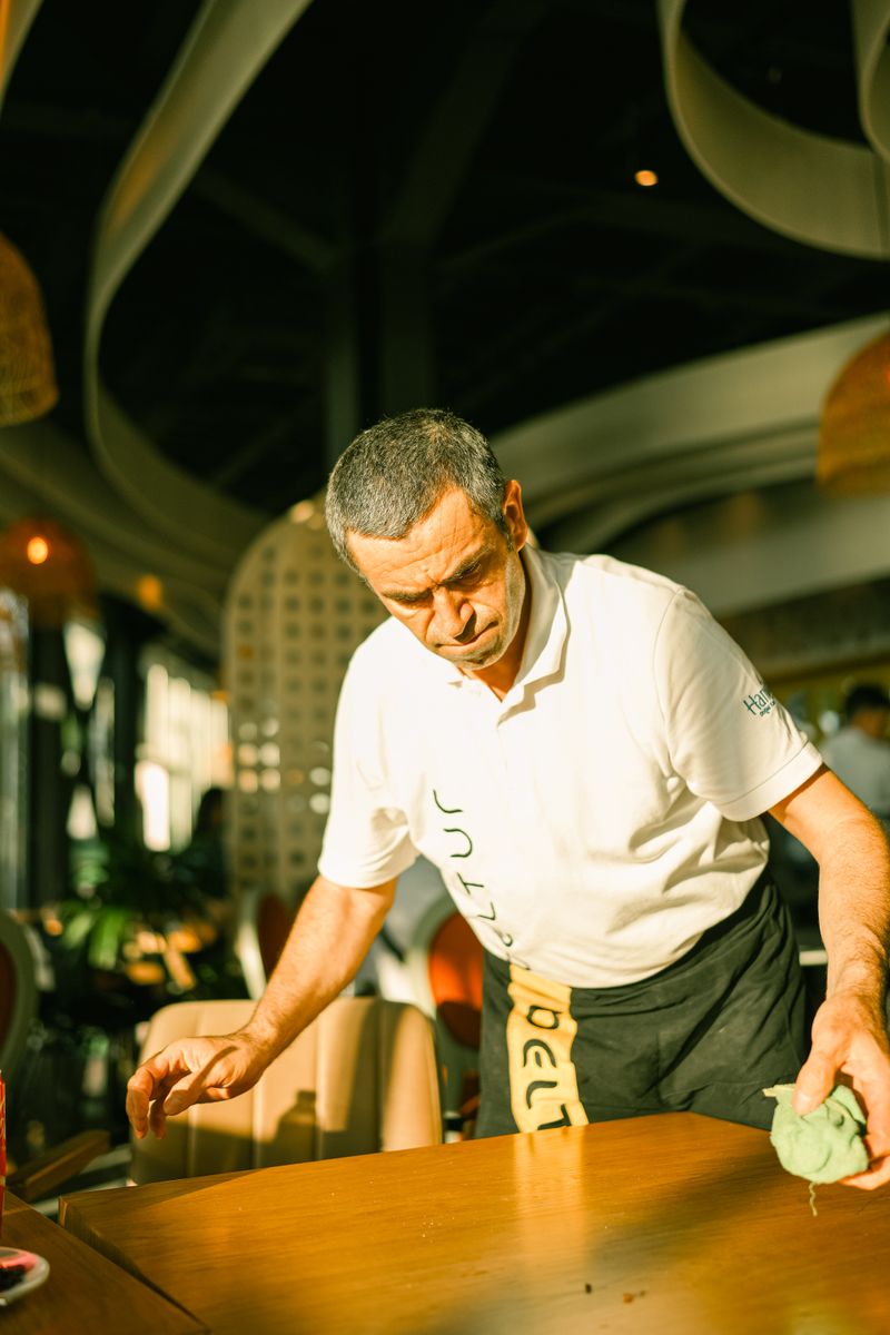 A waiter cleans a table in a bright, modern restaurant, capturing a casual dining atmosphere.