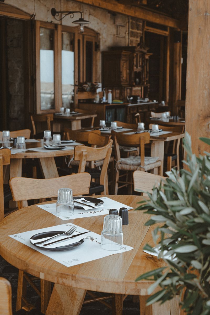 Charming rustic restaurant with wooden tables and set dining places, ready for guests.