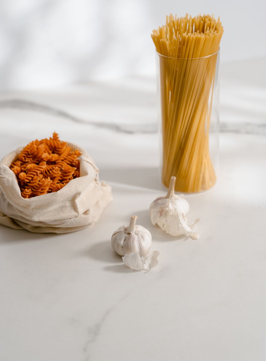 High-quality close-up of raw pasta and garlic on a marble surface, ideal for food-themed projects.