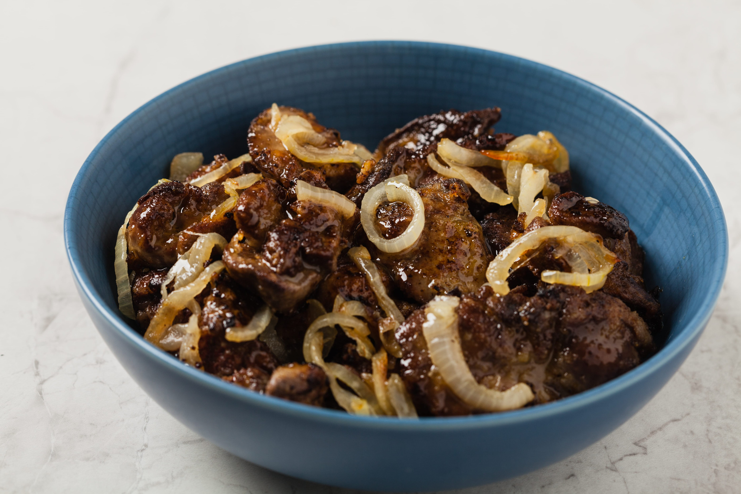 Fried chicken liver with onions. Front view. Stone background.