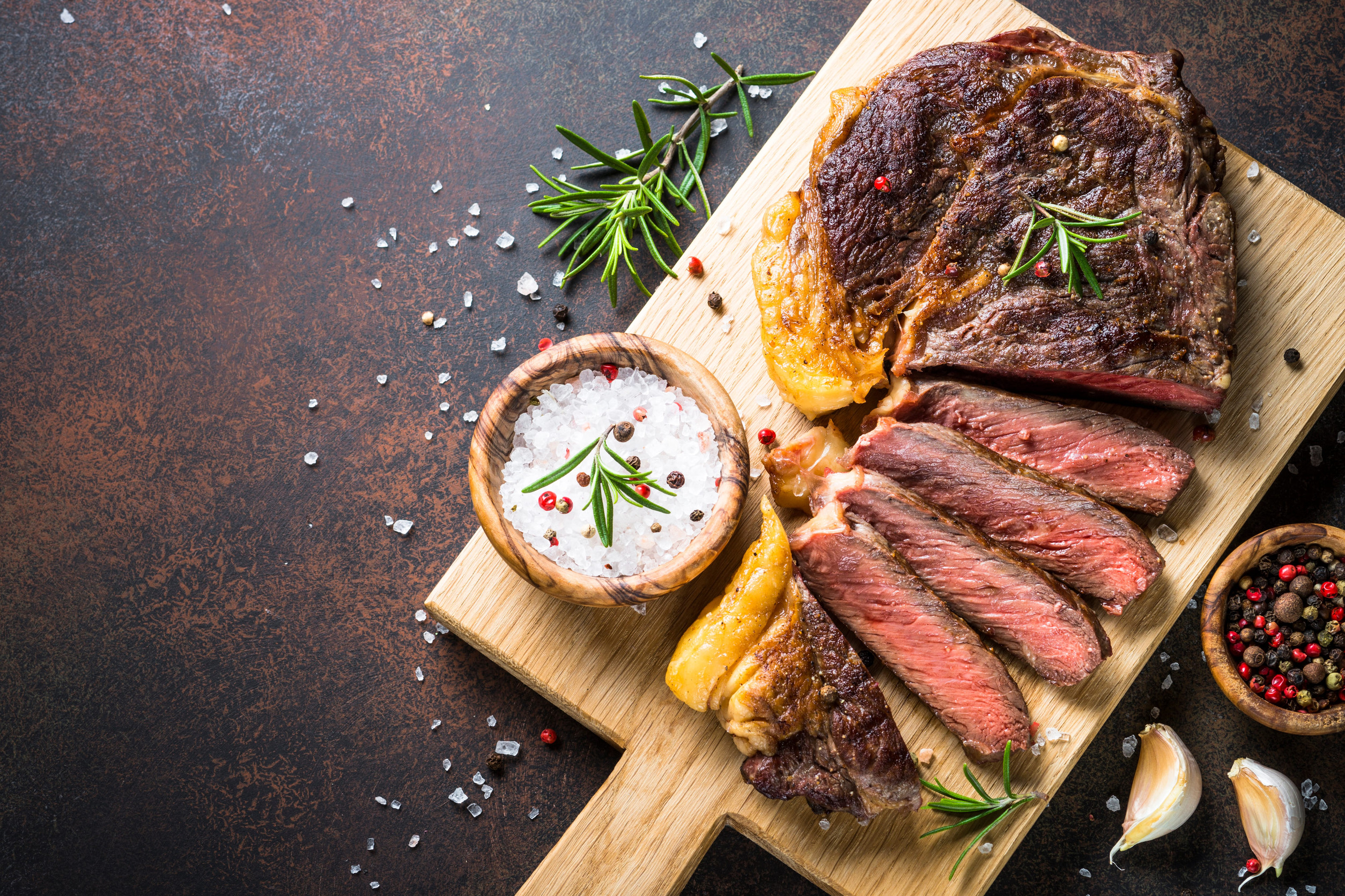 Grilled beef steak ribeye on wooden cutting board.
