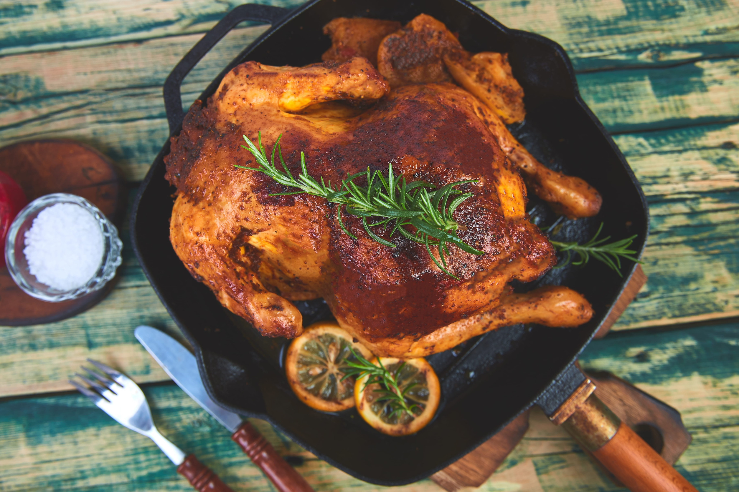 Baked whole chicken with apples in pan on wooden rustic
