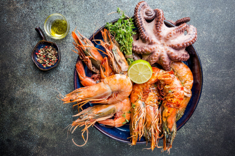 A vibrant seafood platter featuring succulent grilled shrimp and a tender octopus, garnished with fresh herbs and a slice of lime. Perfect for a festive gathering or a gourmet meal at home. Image Credit: roxiller/ 123RF