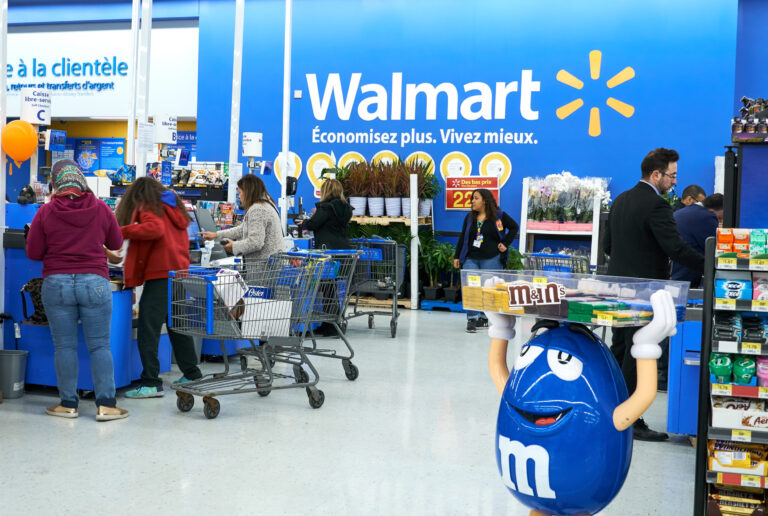 People at cashier in Walmart store. Walmart is an American multinational retail corporation which operates a chain of hypermarkets. Image Credit: dennizn/ 123RF