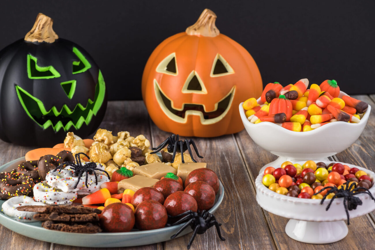 A festive Halloween spread featuring vibrant pumpkin decorations and a variety of spooky sweets. Trick-or-treaters will delight in a colorful assortment of candies, cookies, and treats, all enhanced by playful spider accents that add a touch of fright to the flavorful feast. Image Credit: mickeymousehouse64/ 123RF