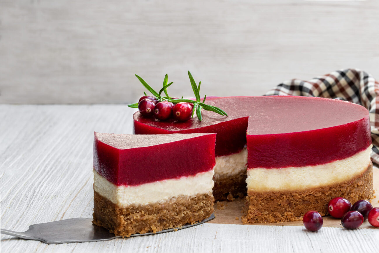 Indulge in a slice of decadence with this luscious layered cheesecake, featuring a rich, creamy filling complemented by a tangy cranberry topping, perfect for festive gatherings or a sweet treat any day. Image Credit: lenazajchikova/ 123 RF