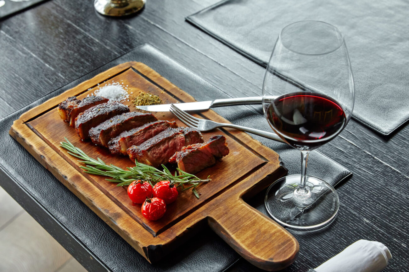 A gourmet steak dinner, beautifully plated with fresh herbs and a glass of rich red wine, inviting you to indulge in a fine dining experience filled with savory flavors and culinary artistry. Image Credit: dimaris2000/123RF