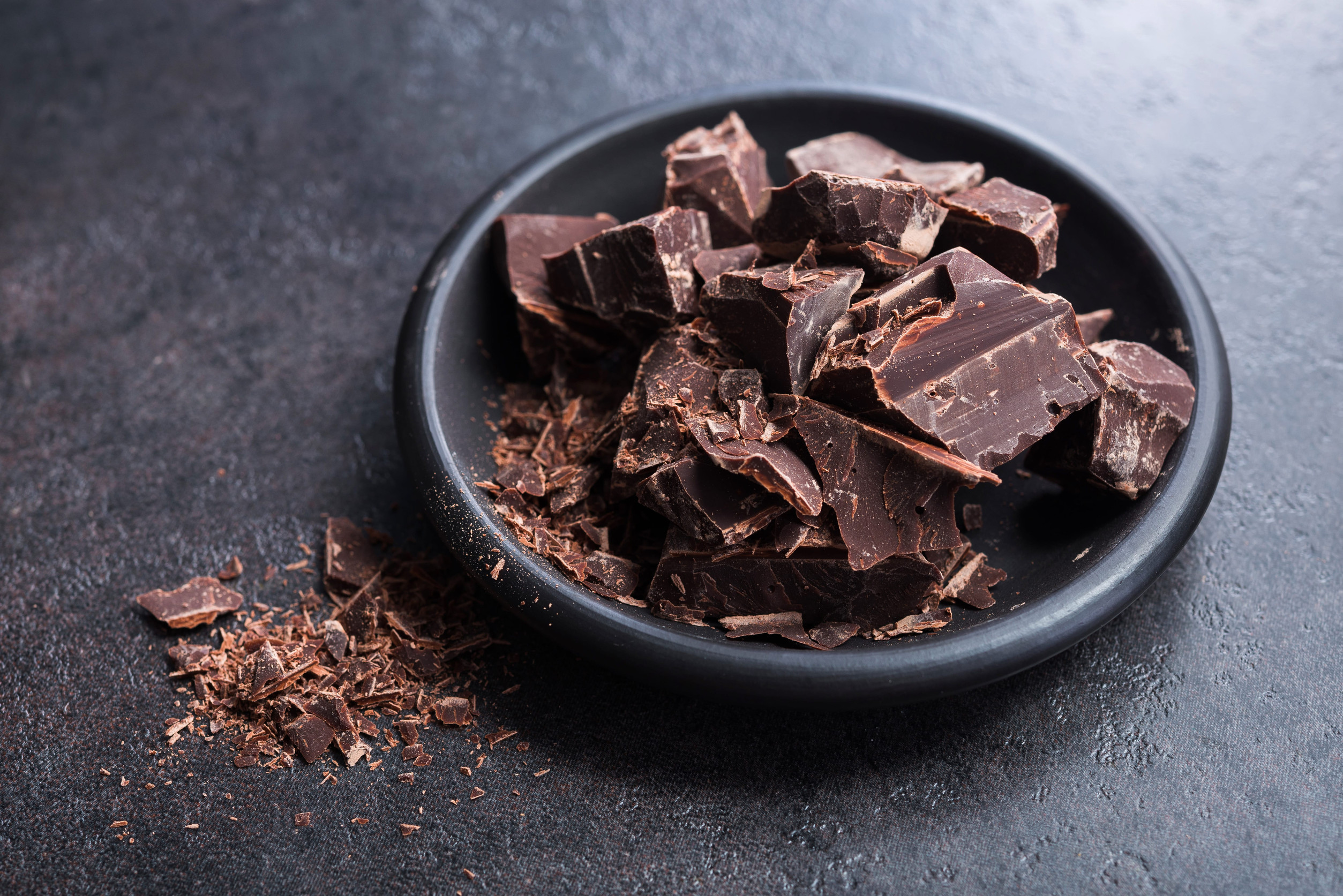 Pieces of chocolate on a plate, stone background.