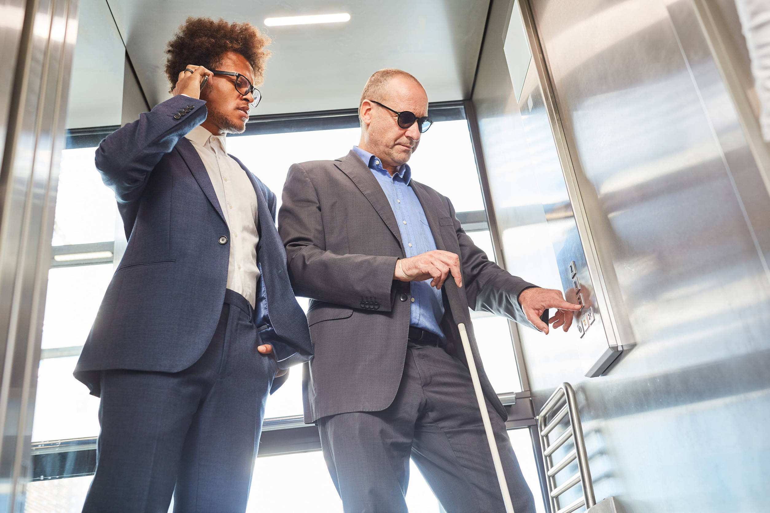 Visually impaired or blind man in the elevator presses button for inclusion concept