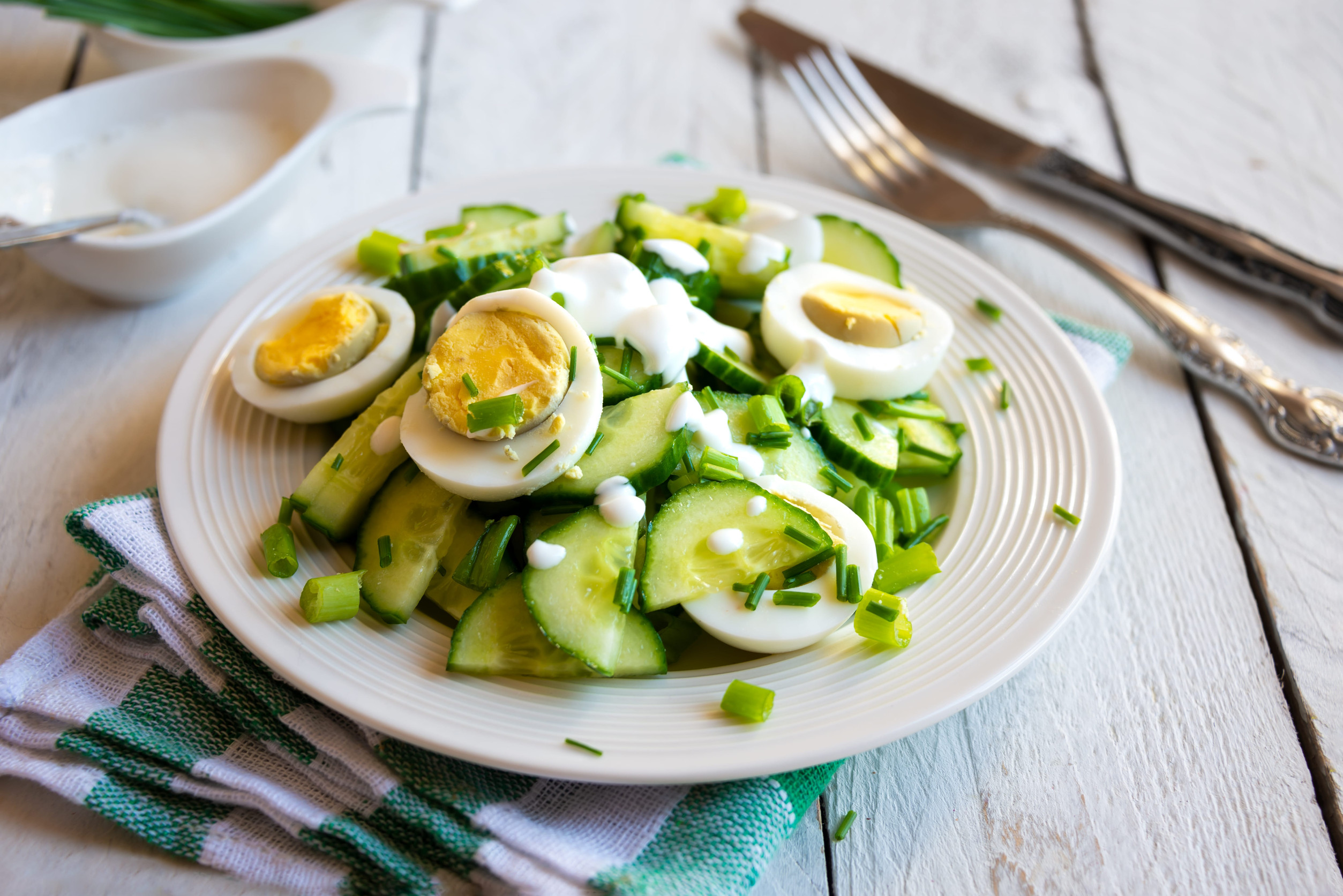 Healthy green salad with cucumbers, eggs, onions and cream