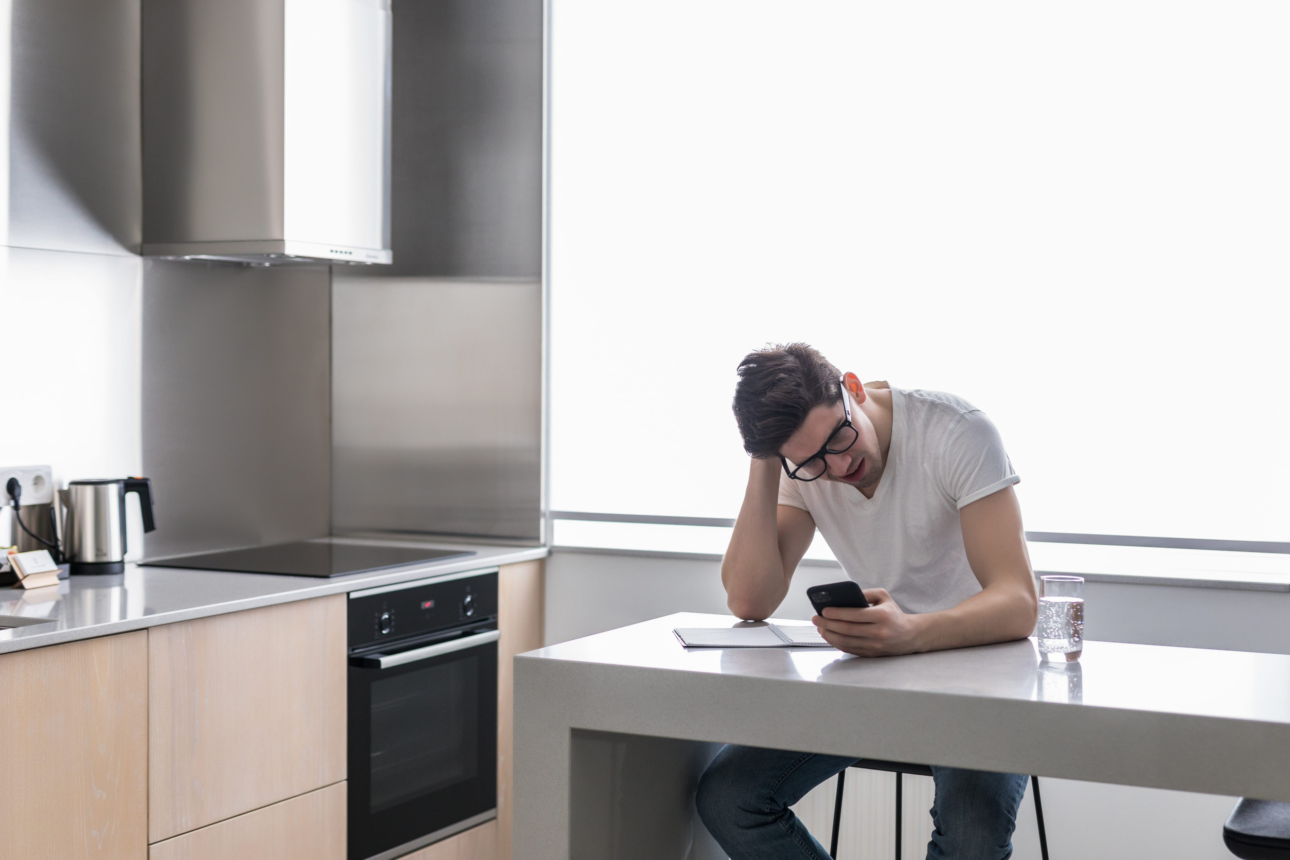 Worried man looking at phone in the kitchen