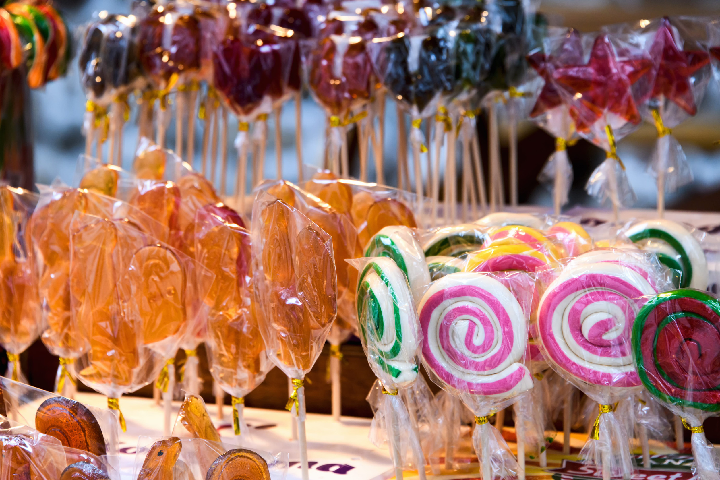Different colorful candy canes caramel on stick. Lollipop on stick in sweets shop window.