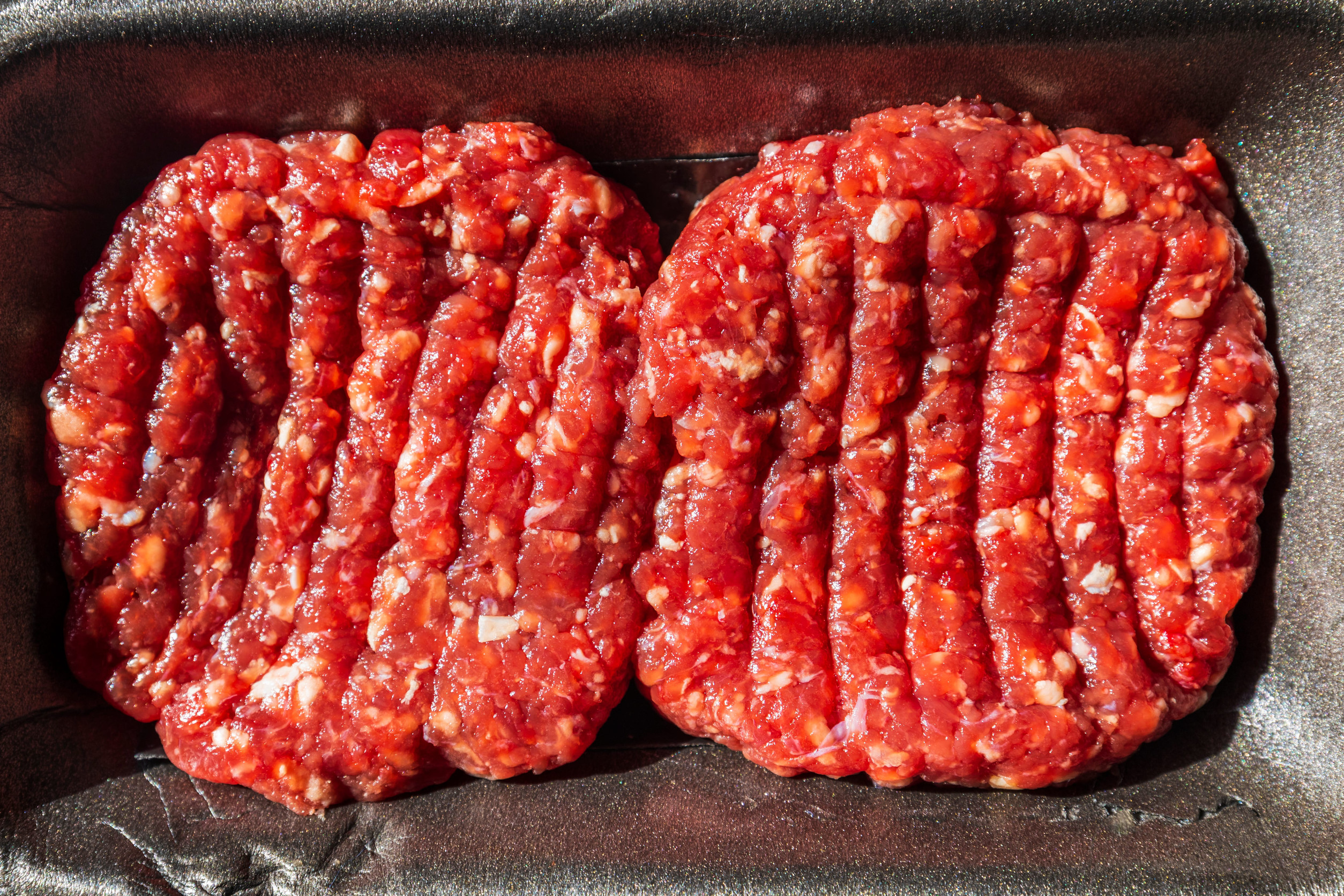 Raw Beef Burgers In A Packaging Tray.