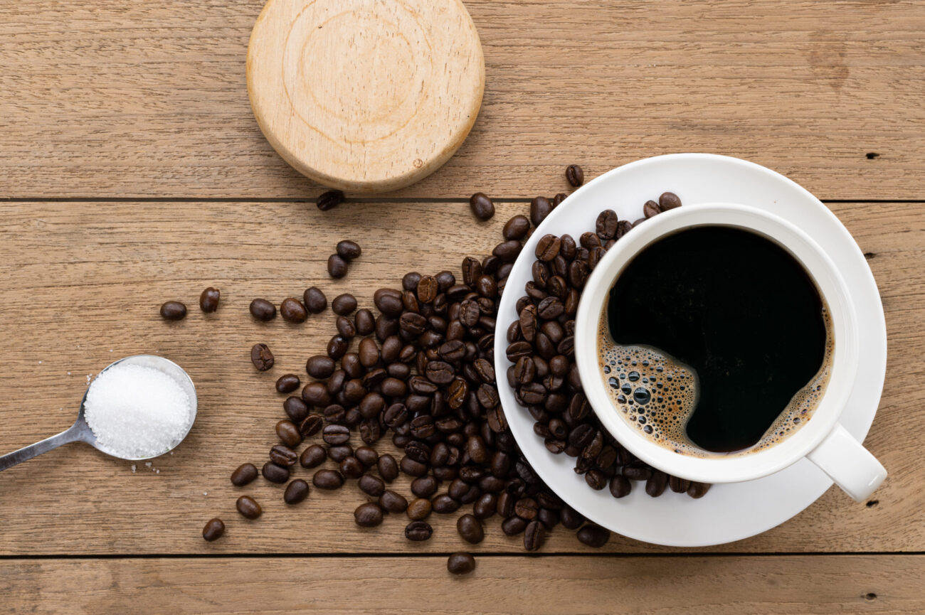 White coffee mug and coffee beans on an old wooden table. Image Credit: nopporn/ 123RF
