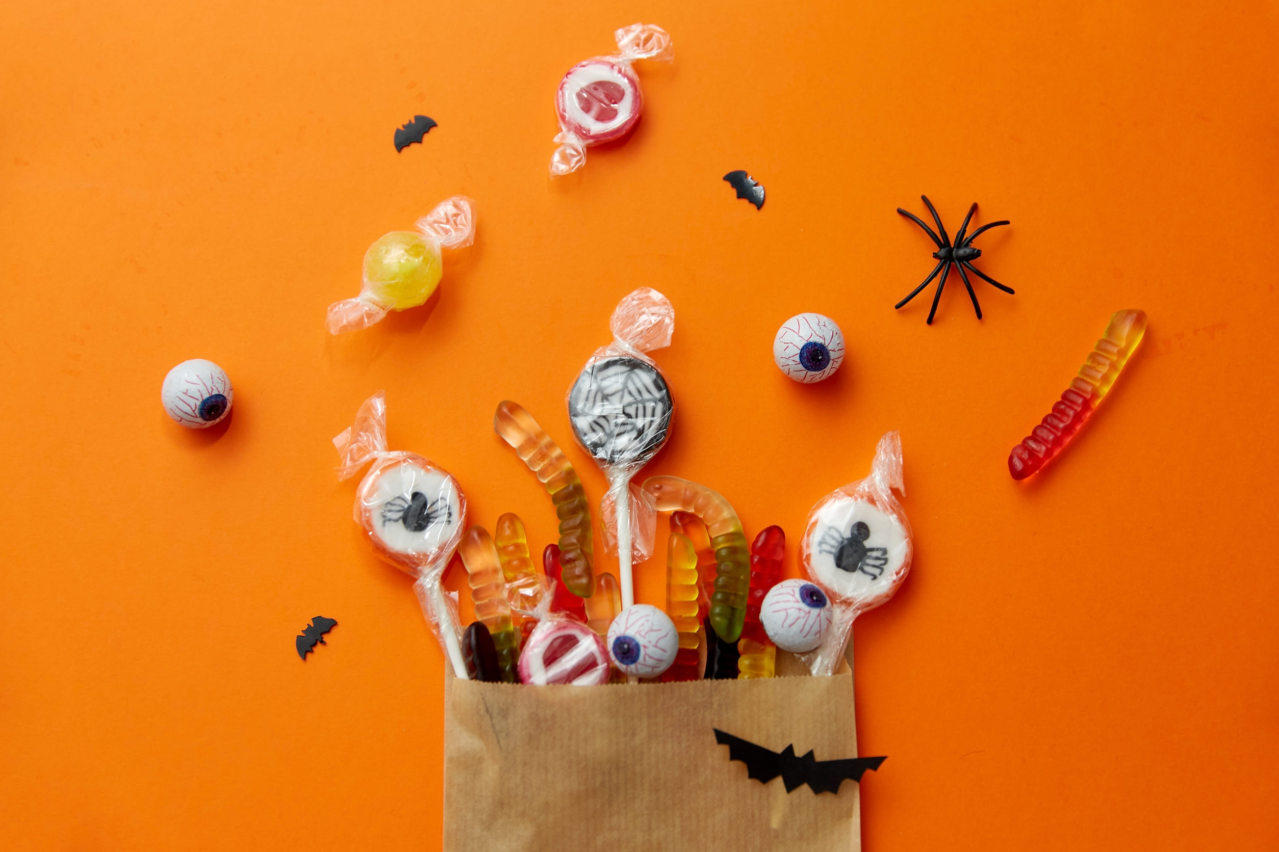 halloween sweets in paper bag on orange background