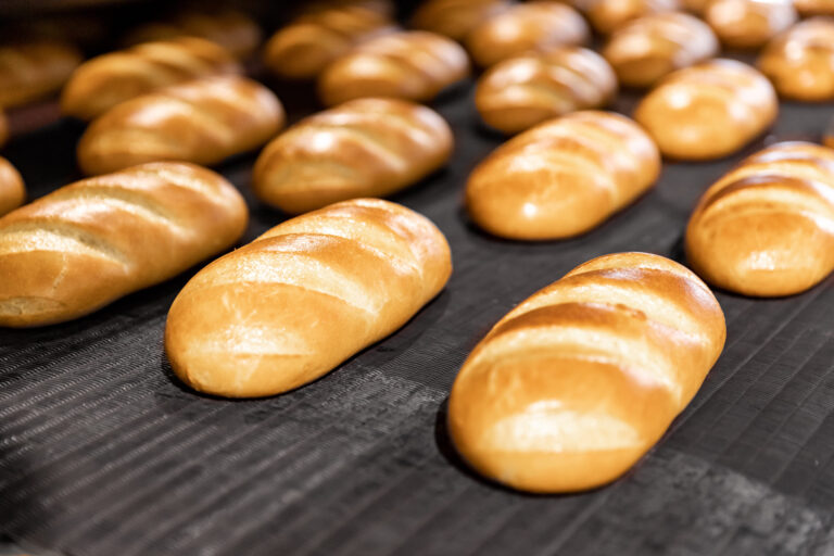 Baked breads on automatic production line bakery from hot oven. Image Credit: parilovv/ 123RF