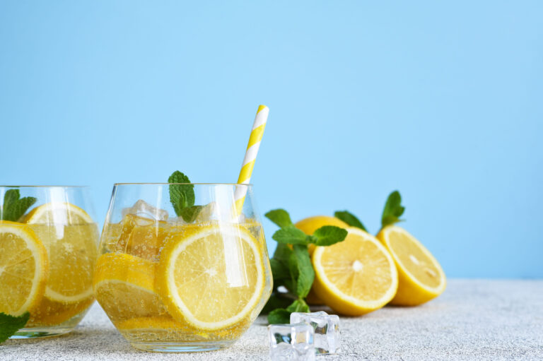 Refreshing summer drinks filled with slices of lemon and garnished with fresh mint leaves create an inviting atmosphere, perfect for warm days spent outdoors. Enjoy the zest of lemon in every sip. Image Credit: zefirchik06/ 123RF