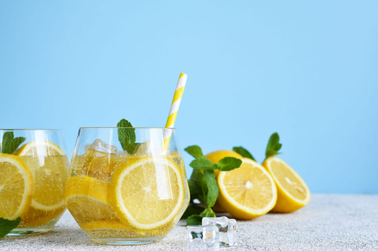 Refreshing summer drinks filled with slices of lemon and garnished with fresh mint leaves create an inviting atmosphere, perfect for warm days spent outdoors. Enjoy the zest of lemon in every sip. Image Credit: zefirchik06/ 123RF