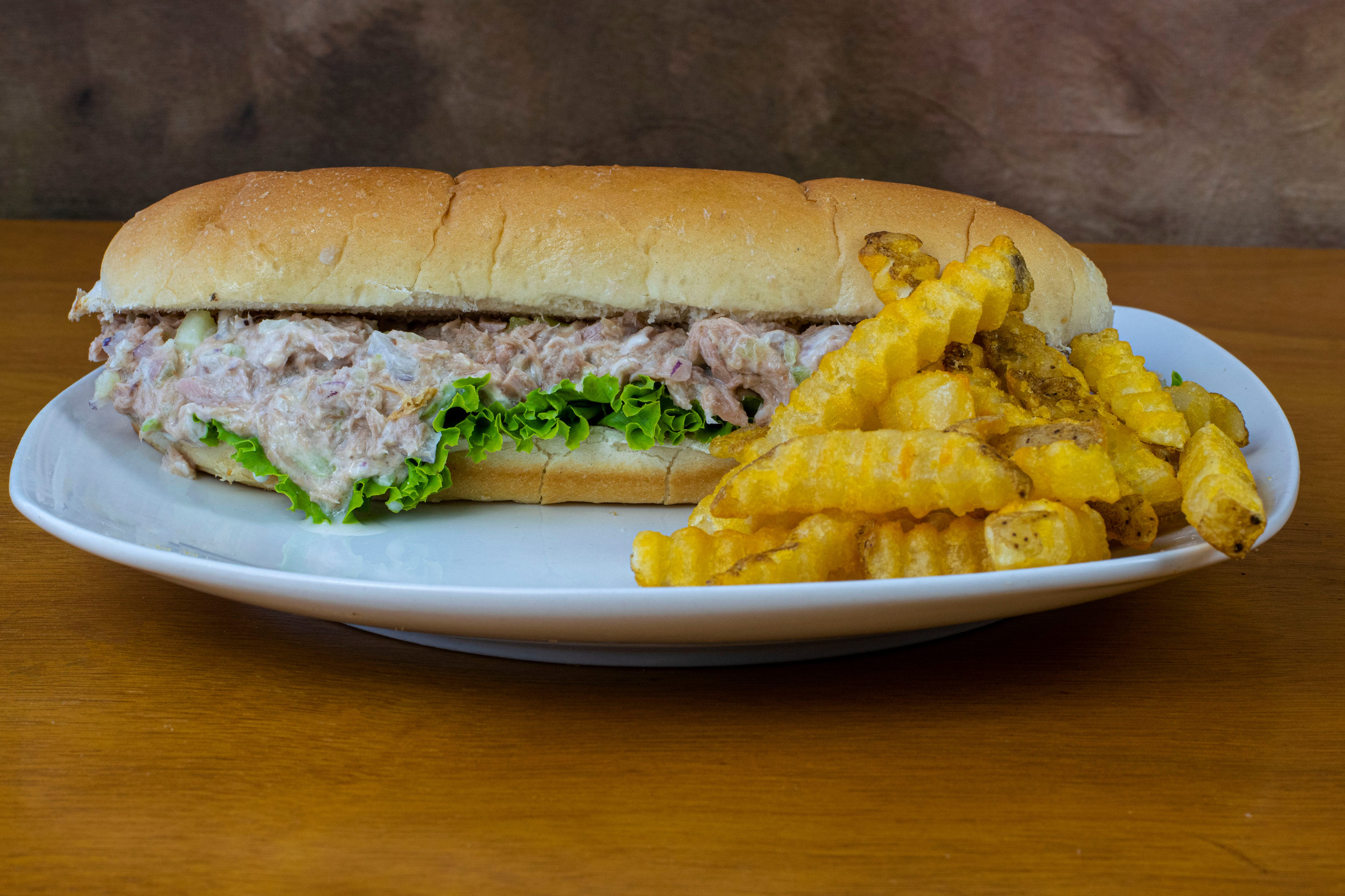 tuna salad sub served with a side of fries