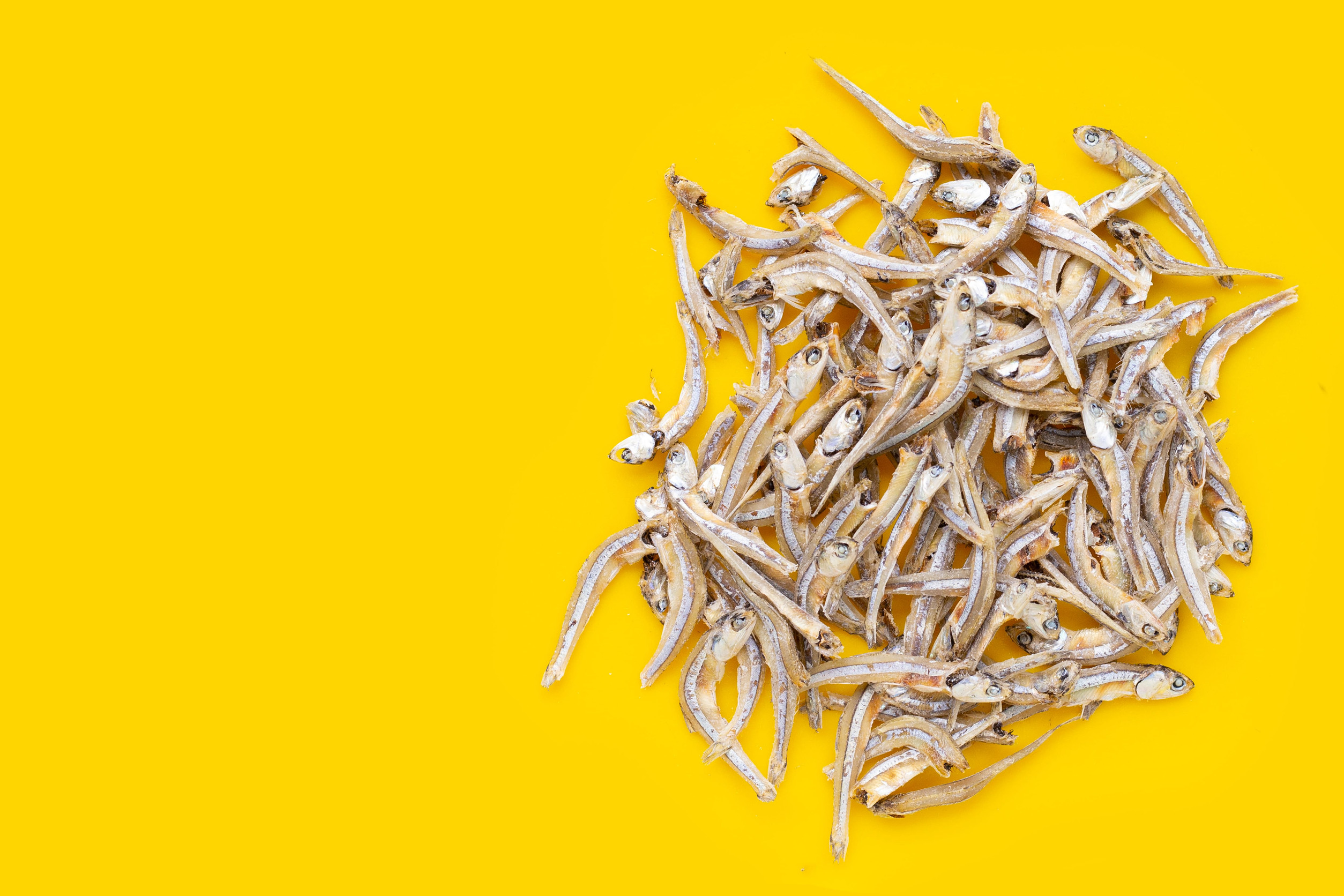 Dried anchovy on yellow background.