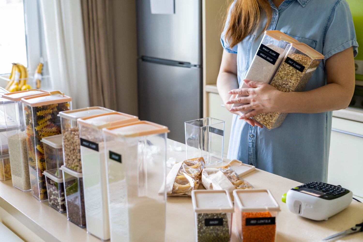 In a modern kitchen filled with organized containers, a woman carefully collects ingredients for her next culinary adventure. Image Credit: kostikova/ 123RF