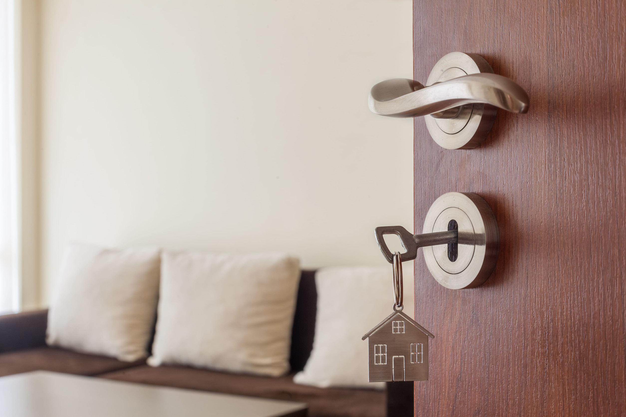 Open door to a new home. Door handle with key and home shaped keychain. Mortgage, investment, real estate, property and new home concept
