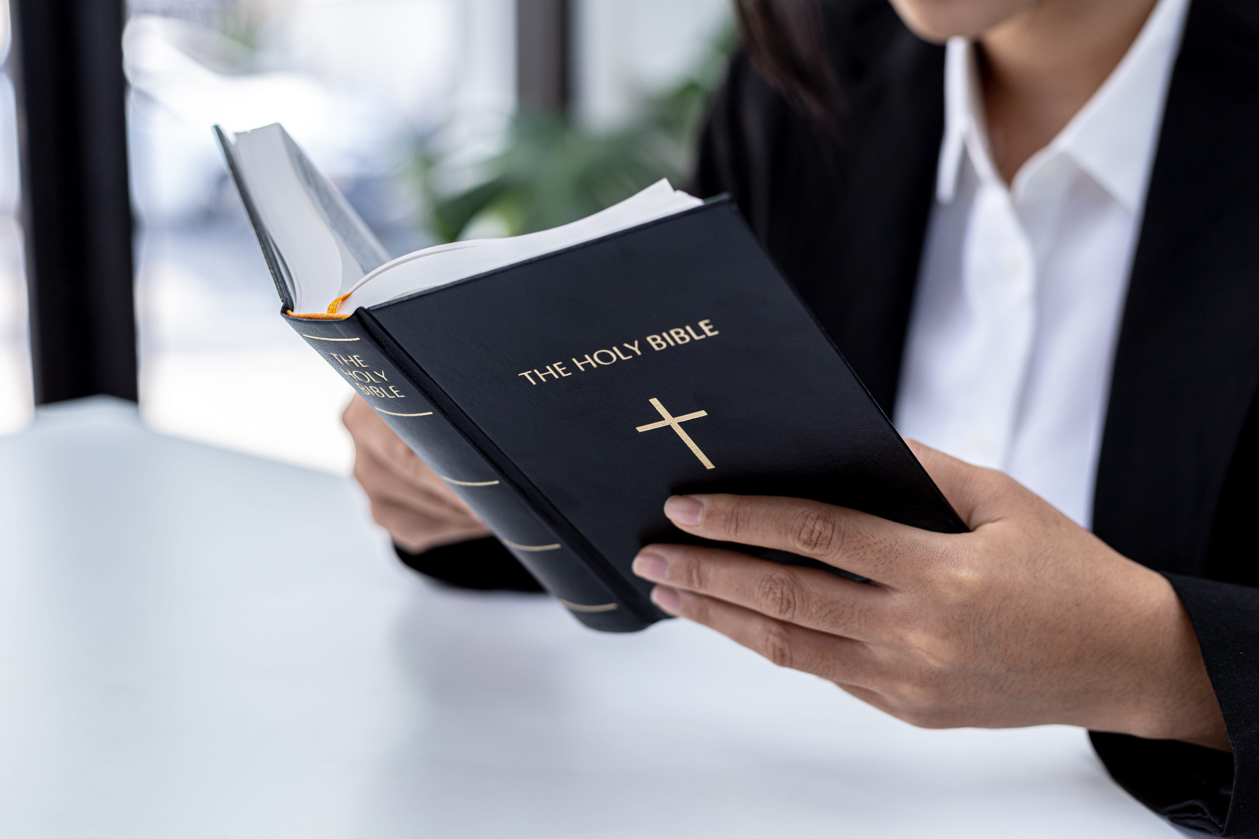 A person is reading the Bible, he is praying to the Bible, he is reading and studying the Bible. Concept of Christianity and Bible Study.