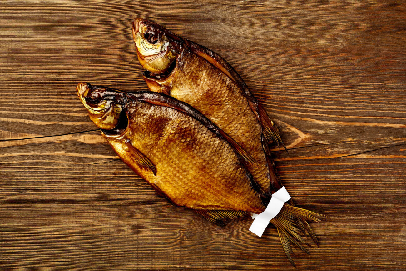 Two perfectly smoked fish resting on a rustic wooden table, showcasing a culinary delight that's both traditional and savory, inviting anyone to enjoy the simple pleasures of life. Image Credit: tommisch/ 123RF