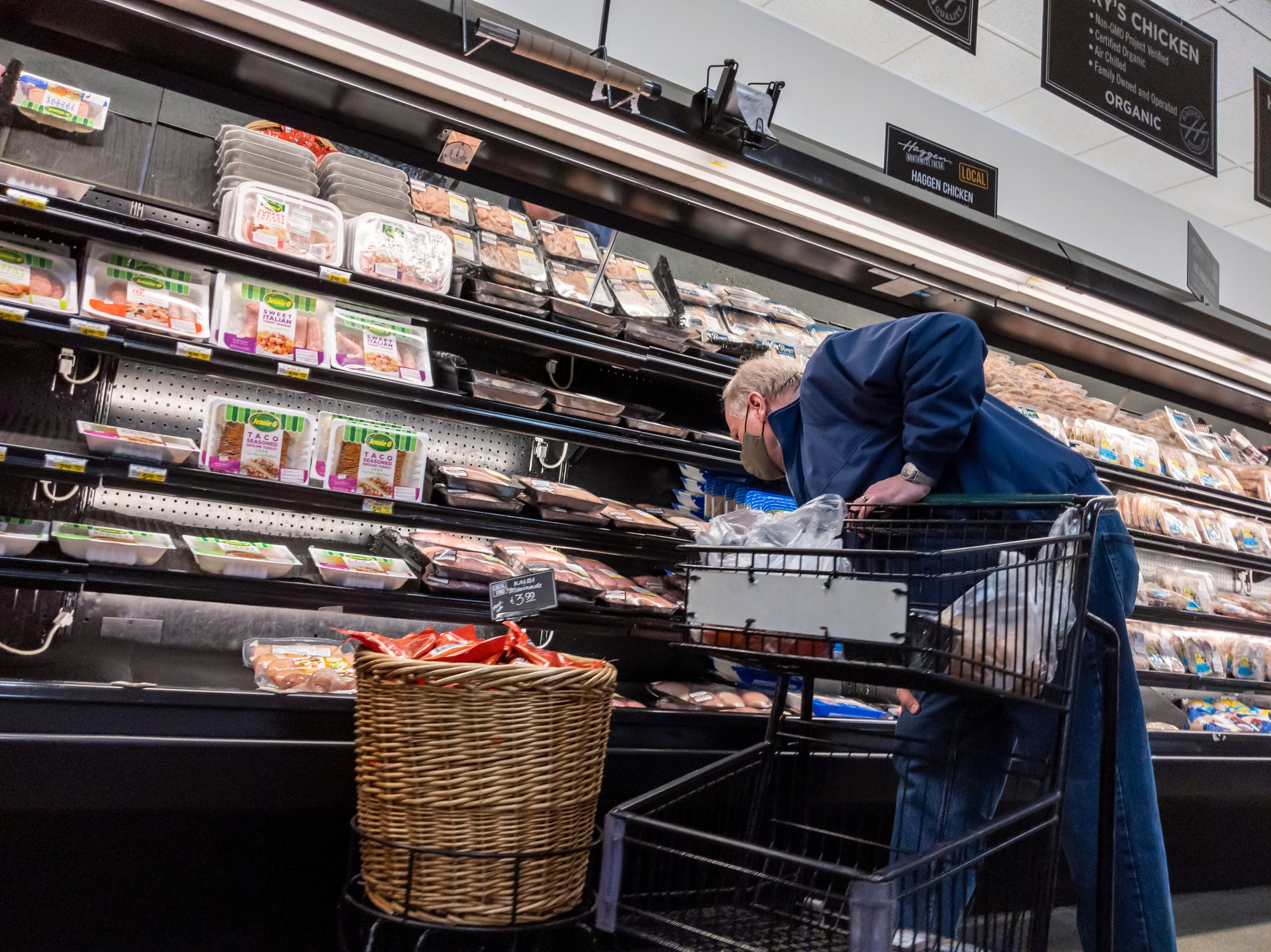 Woodinville, WA USA - circa January 2022: View of an elderly man shopping in the meat department of a Haggen grocery store during the covid 19 pandemic.