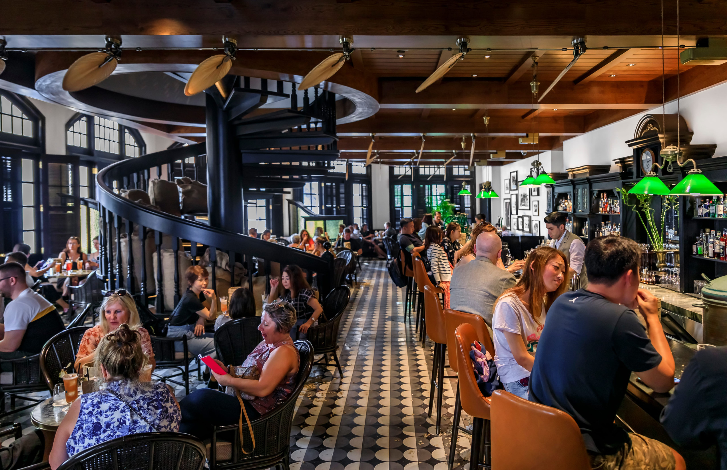 Singapore - September 08, 2019: Customers at the Long Bar at the iconic Raffles Hotel, famous for inventing the Singapore Sling