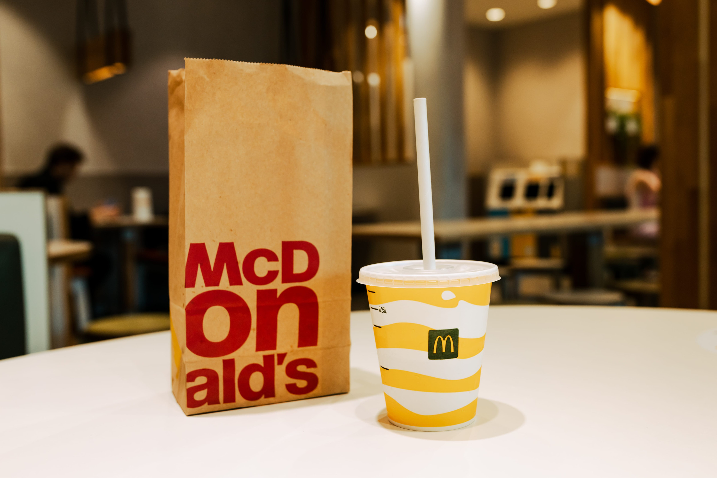 11.06.2022 Poland, Warsaw - The takeout packaging paper bag for McDonalds with drink placing on the table. Illustrative Editorial product photo