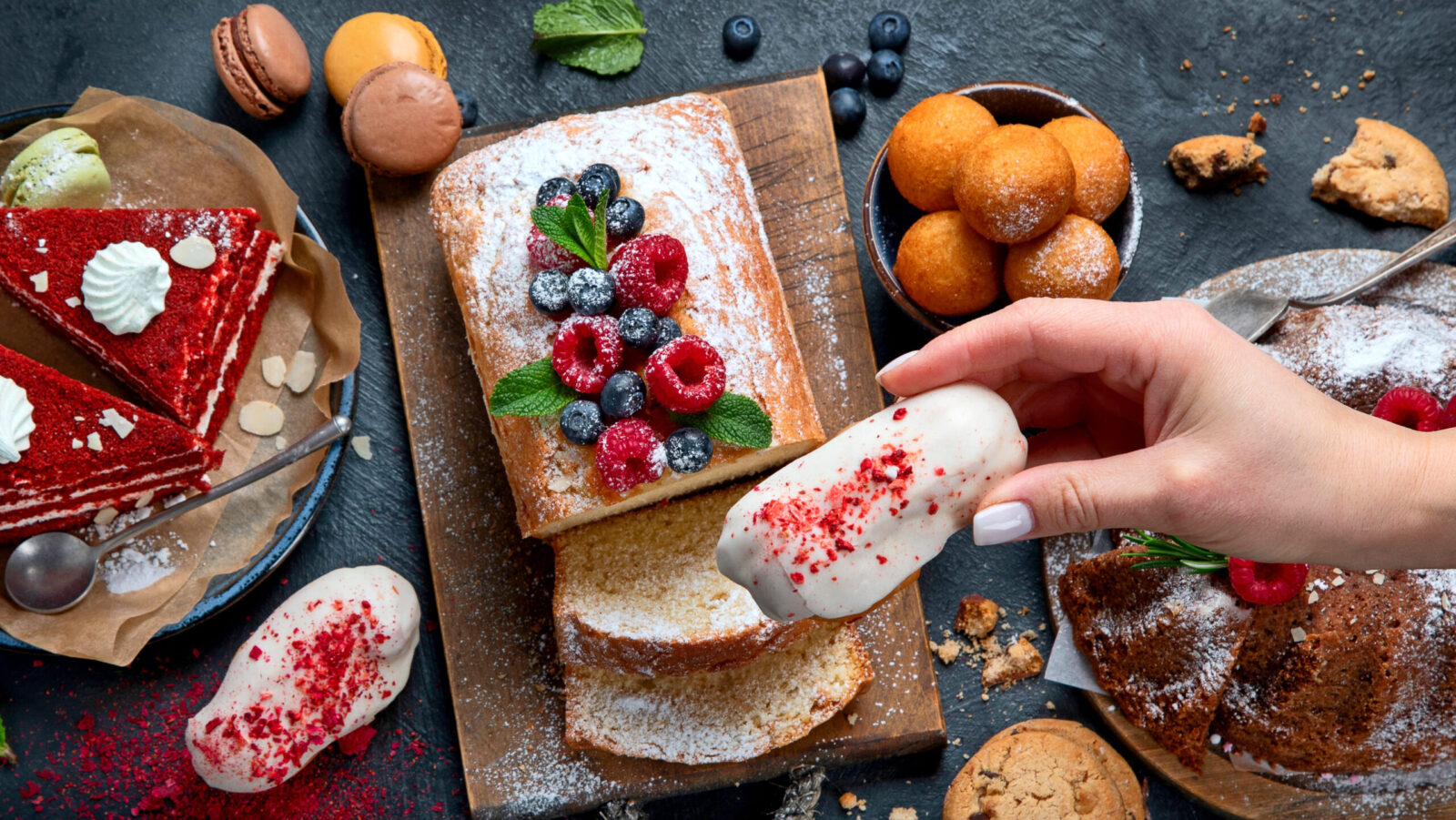 Indulge in a delectable dessert spread featuring a beautifully decorated cake topped with fresh berries, alongside an array of cookies and pastries. Image Credit: baibakova/ 123RF
