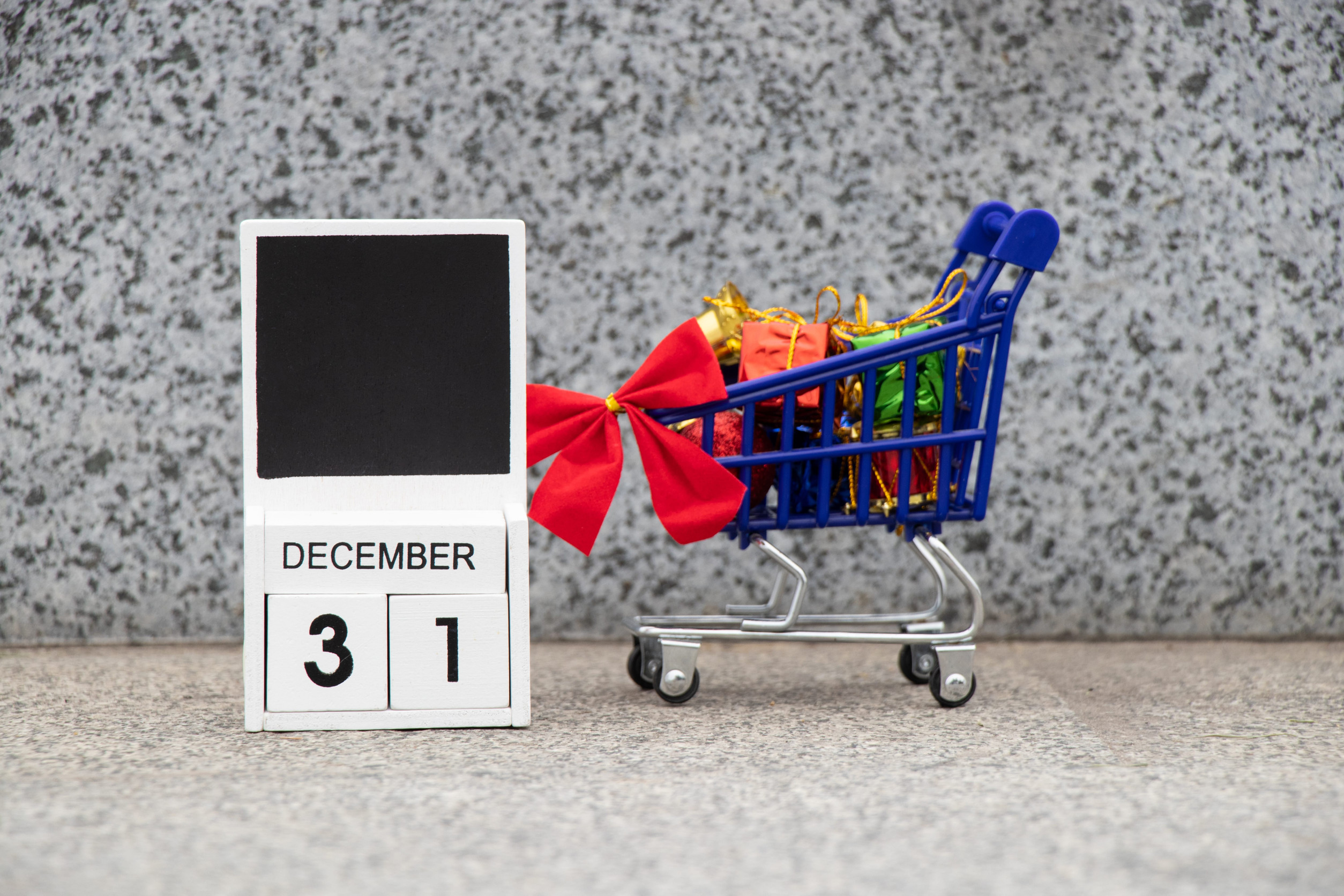 December 31 is written on a wooden plate in the calendar, and next to it is a cart from a supermarket with gifts on the street, happy new year, new year holiday