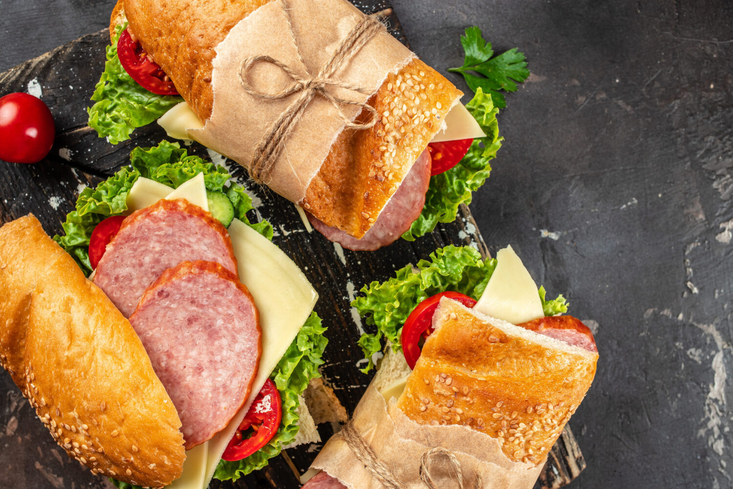 Indulge in a delightful sandwich feast featuring freshly baked bread, layers of savory meats, crisp lettuce, and ripe tomatoes, perfect for a sunny picnic or a cozy lunch at home. Image Credit: kovalnadiya/ 123RF