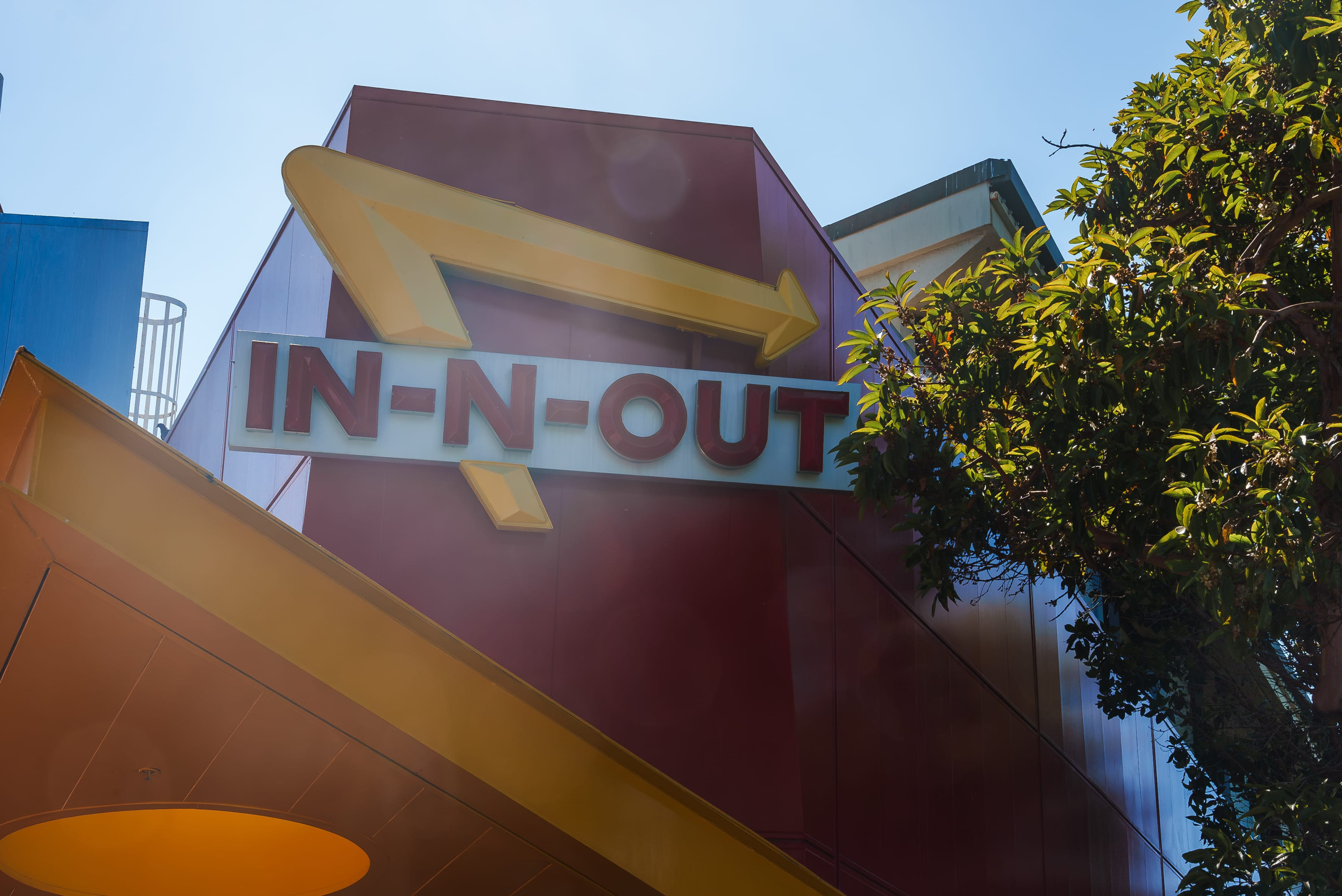 In N Out Burger iconic sign, red background, yellow arrow, building mount in San Francisco.