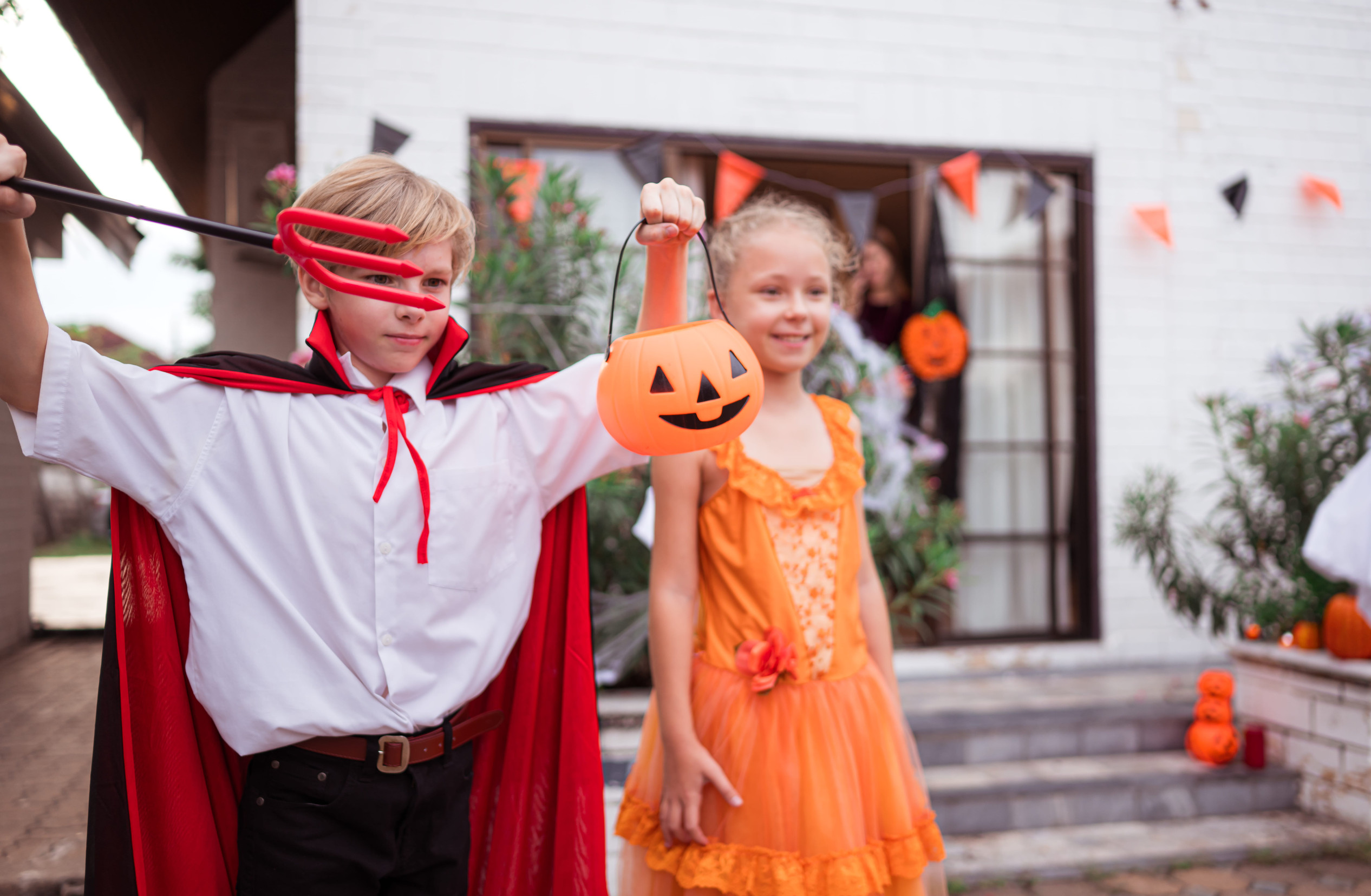 Children in ghost costumes are having fun trick-or-treating on Halloween