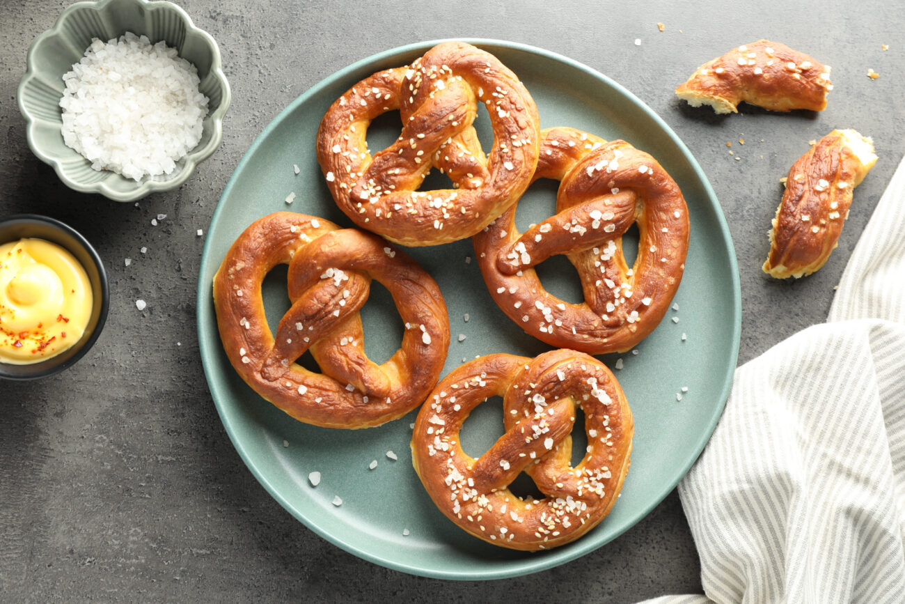 Tasty pretzels with salt and sauce on gray table. Image Credit: liudmilachernetska/ 123RF