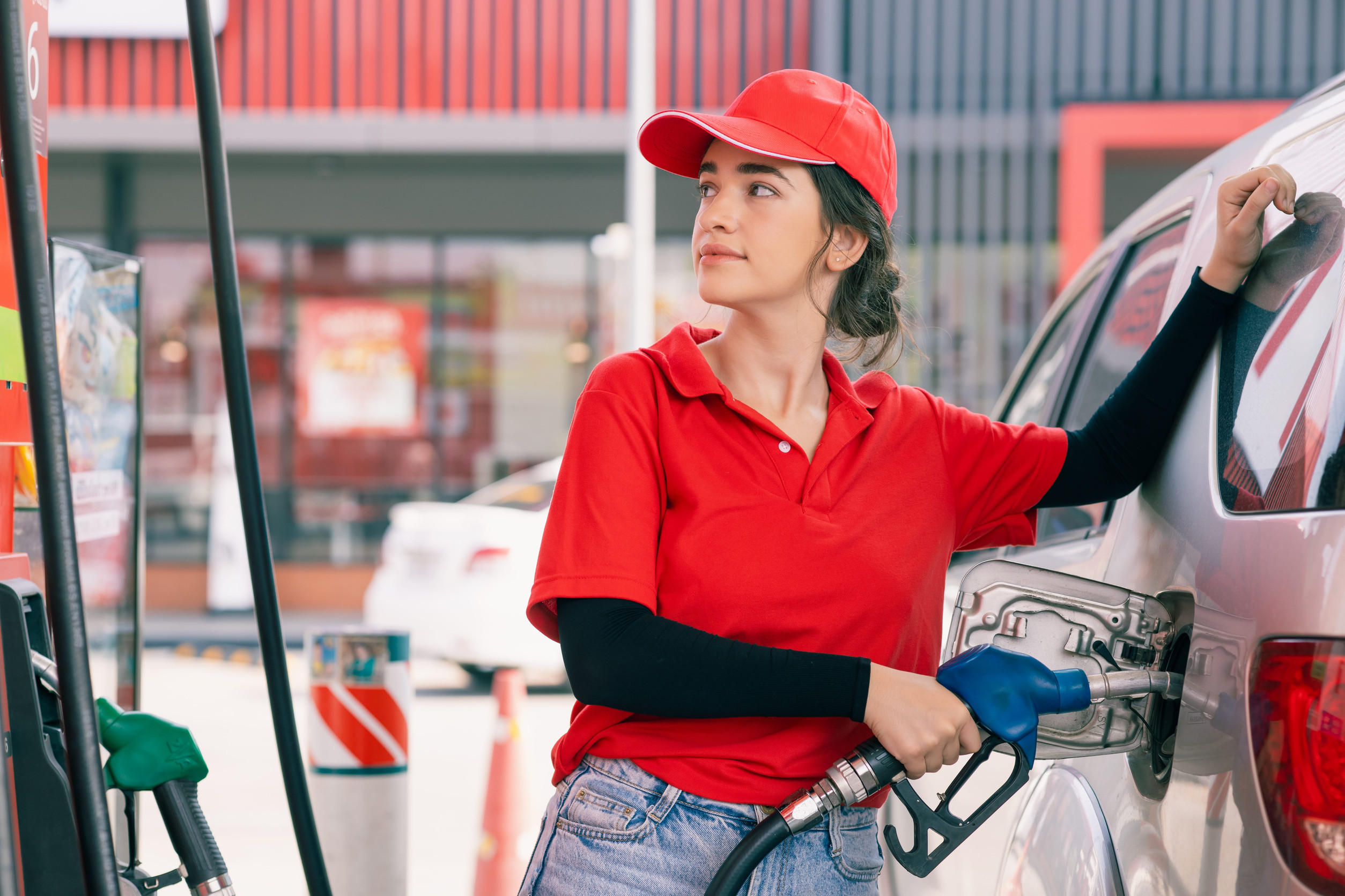 Happy gas station staff worker latin women handle fuel nozzle for refill car fuel, Petroleum business market industry concept