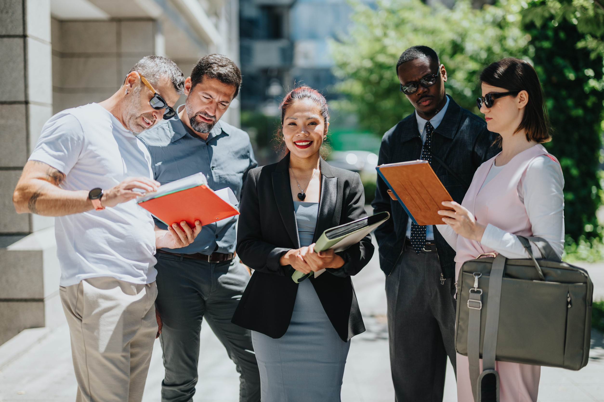 Group of diverse coworkers collaborating outdoors on a sunny day