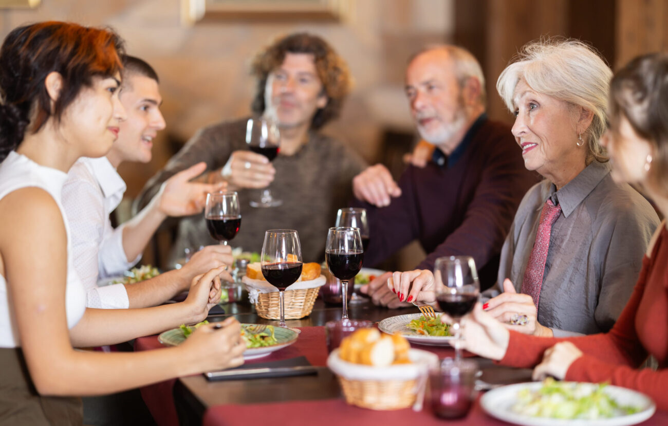 Family members enjoying dinner with warm conversation in restaurant. Image Credit: jackf/ 123RF