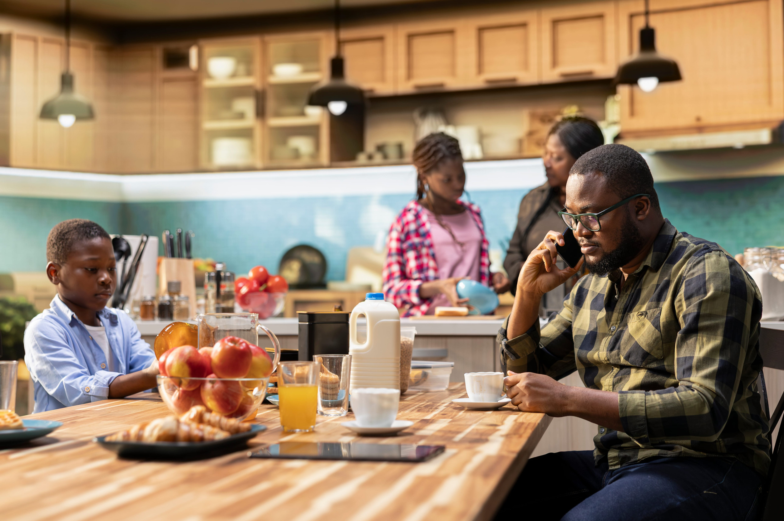 Black young dad on a phone call for work during breakfast meal together, interrupting family bonding time and morning routine to answer important calls. Father neglecting his children.