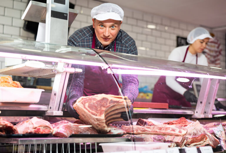Adult man puts beef ribs in showcase