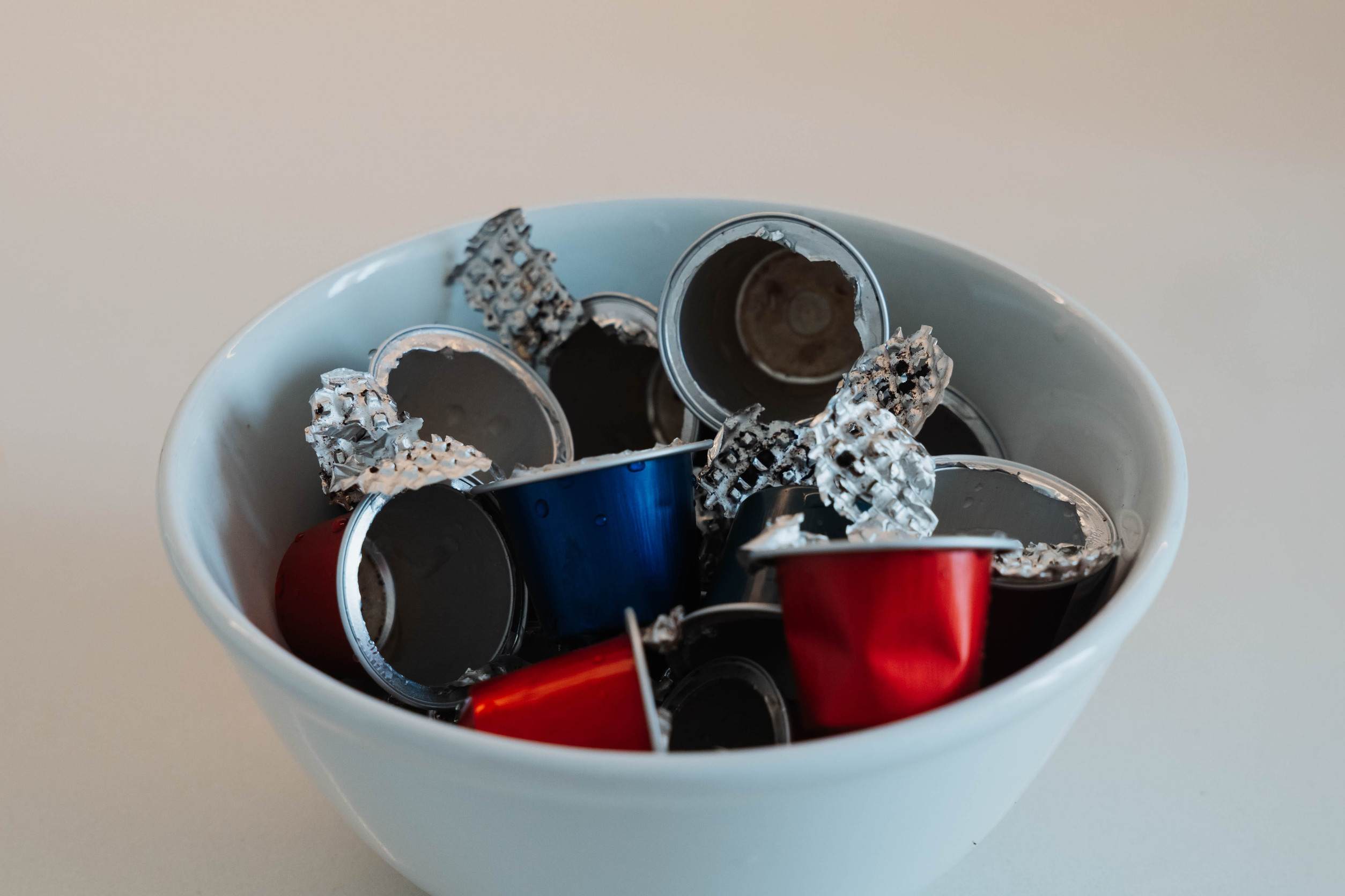 Used coffee capsules rinsed and separated on a kitchen counter for waste sorting. Separate clean aluminum coffee pods from organic waste for recycling and responsible resource recovery.