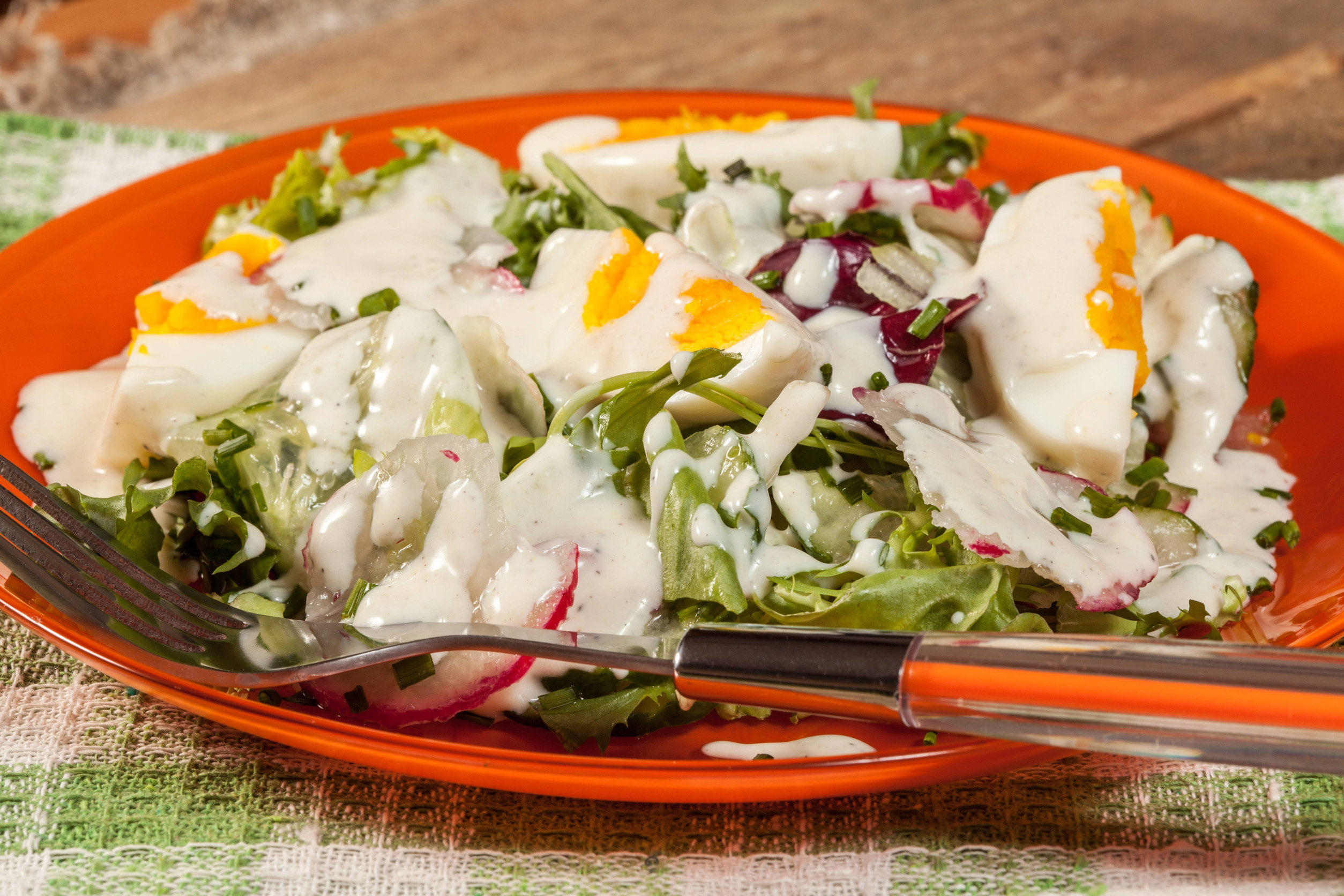 Salad with egg, radish and cucumber in bowl.