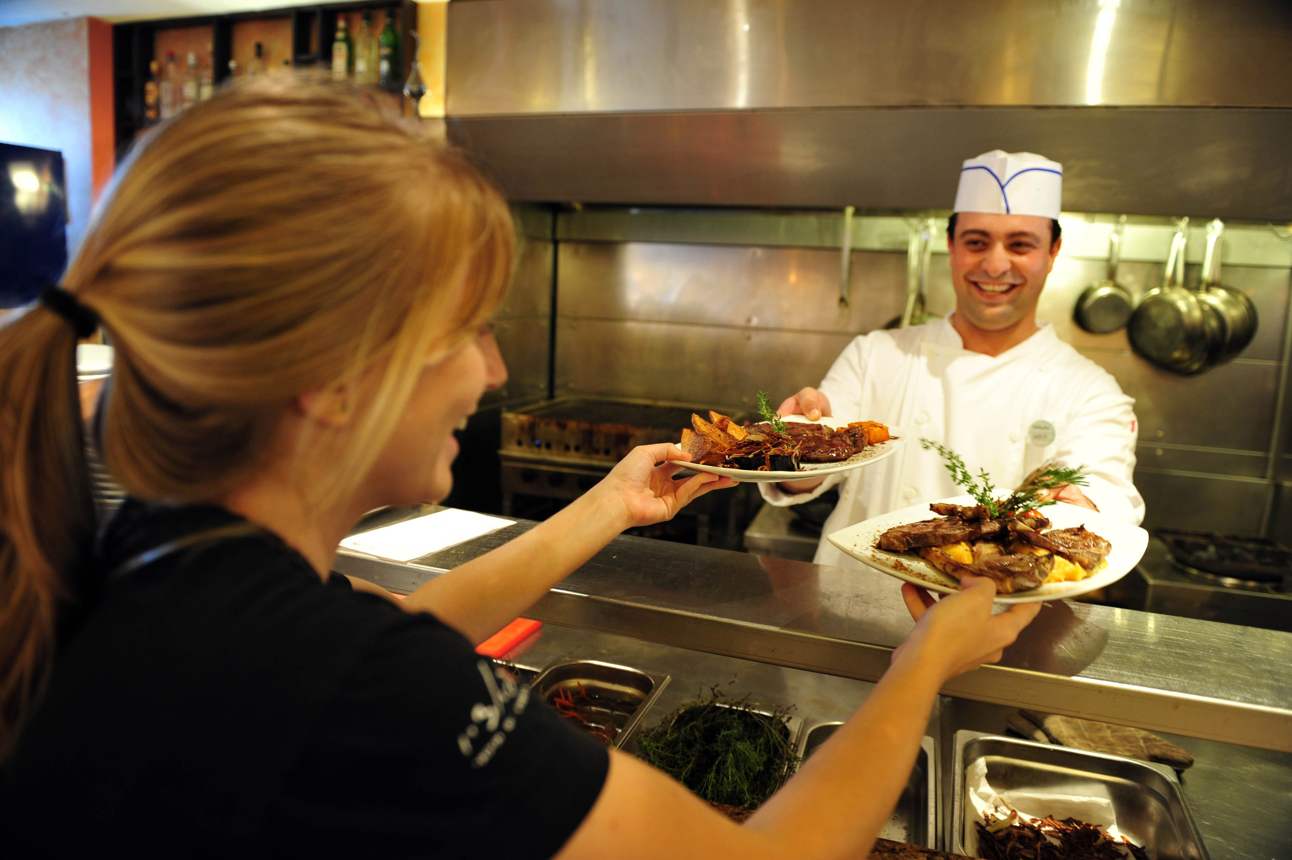 ASHKELON - JULY 27: Chef passing delicious food to a woman waitress in a restaurant on July 27 2009, in Ashkelon, Israel.