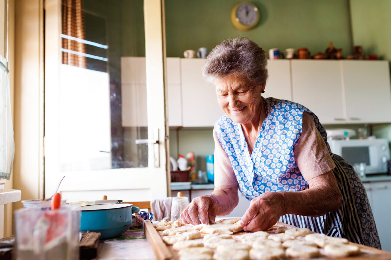 In a cozy kitchen filled with the aroma of fresh pastries, an elderly woman skillfully crafts homemade dough. Her experienced hands work with precision, shaping the dough into delightful treats, showcasing both tradition and love. Image Credit: halfpoint/ 123RF
